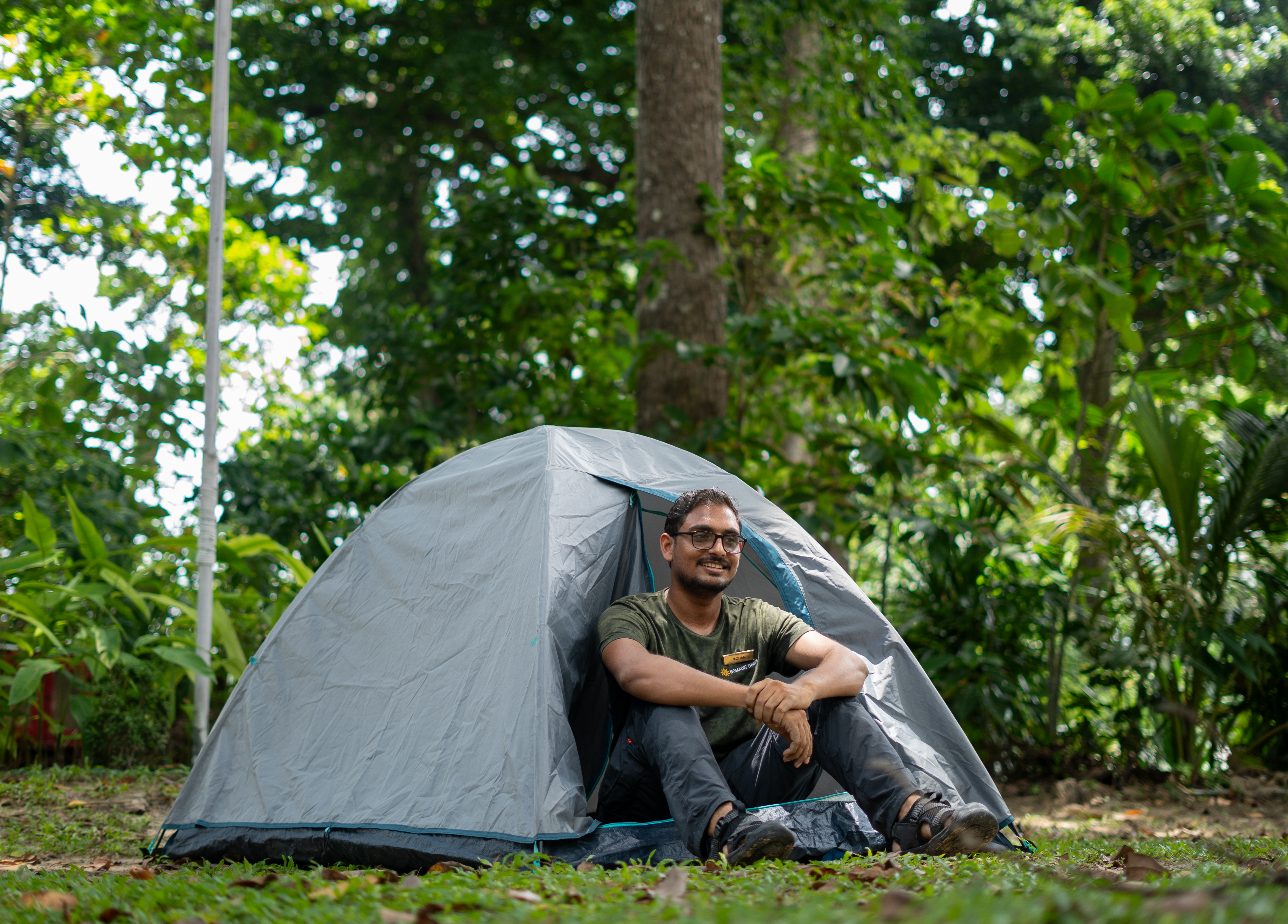 A Nomadic Tribes guide sitting at the entrance of a pitched tent during a Bush Craft session, Havelock Island